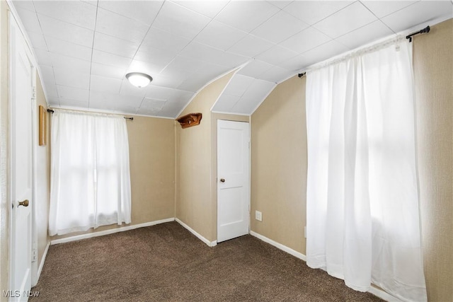 additional living space featuring lofted ceiling, baseboards, and dark colored carpet