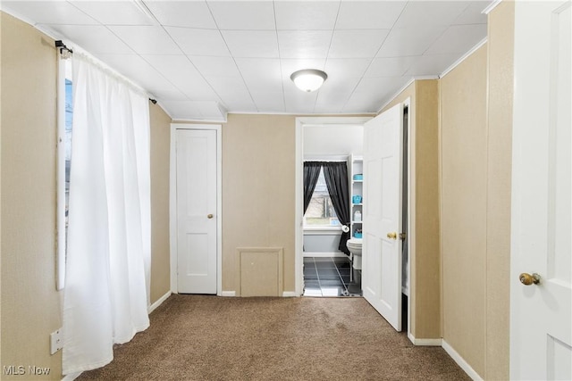 interior space with baseboards, connected bathroom, ornamental molding, and carpet flooring