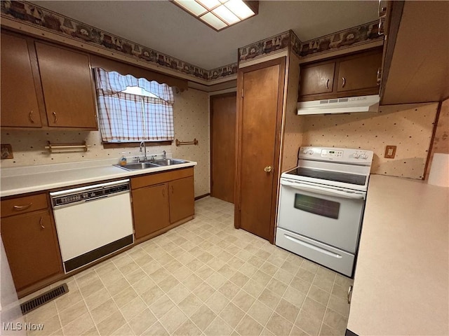 kitchen featuring white appliances, visible vents, light countertops, under cabinet range hood, and a sink