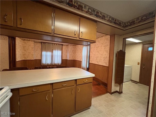 kitchen featuring wallpapered walls, range, a wainscoted wall, light countertops, and light floors