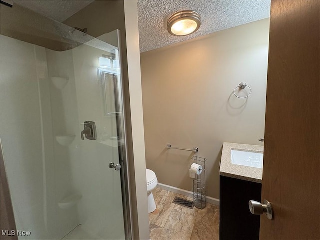 bathroom featuring baseboards, toilet, a textured ceiling, vanity, and a shower stall