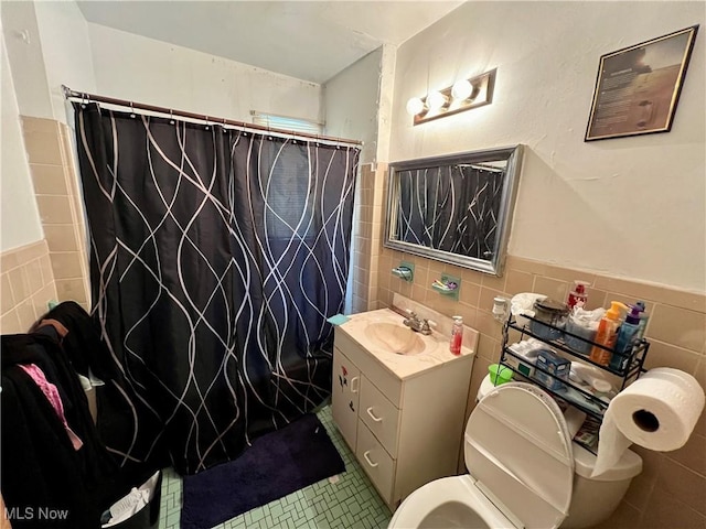 full bath with toilet, a shower with shower curtain, vanity, tile walls, and tile patterned floors