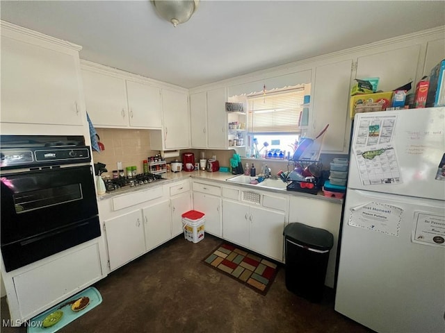 kitchen featuring light countertops, stainless steel gas stovetop, freestanding refrigerator, white cabinets, and oven