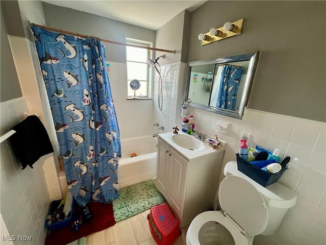 bathroom with shower / bathtub combination with curtain, tile walls, toilet, and vanity