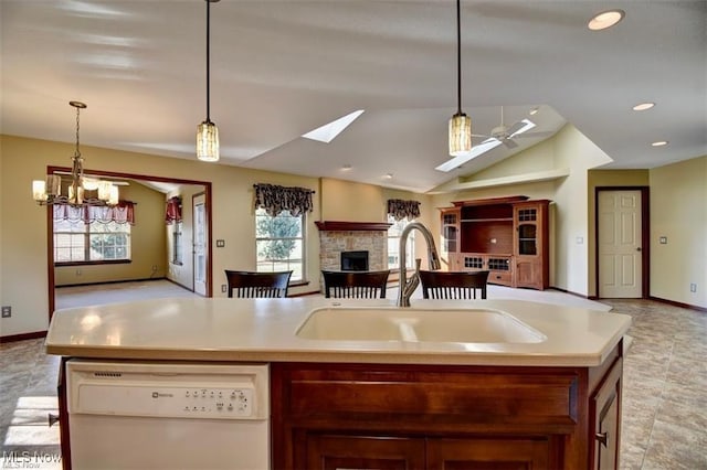 kitchen featuring a fireplace, light countertops, open floor plan, white dishwasher, and a sink