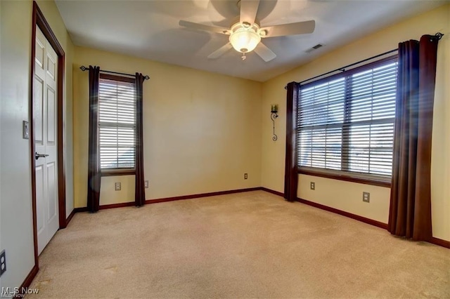 empty room featuring light carpet, plenty of natural light, visible vents, and baseboards