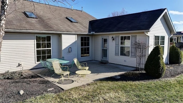 rear view of house featuring roof with shingles and a patio area