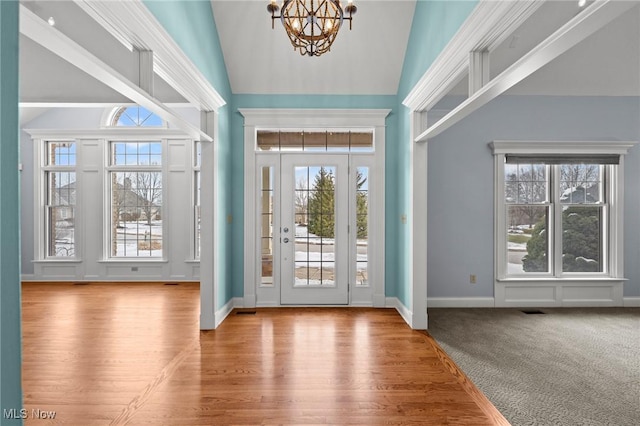 doorway to outside featuring a chandelier, high vaulted ceiling, carpet floors, wood finished floors, and visible vents