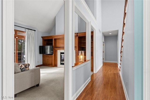 hall featuring high vaulted ceiling, baseboards, and wood finished floors