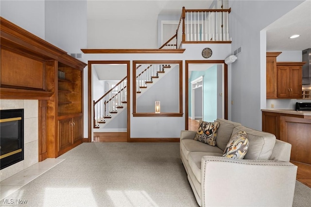 unfurnished living room with carpet, stairs, visible vents, and a tiled fireplace