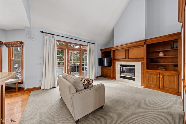 living area featuring high vaulted ceiling, a fireplace, and baseboards