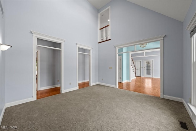 unfurnished bedroom with high vaulted ceiling, carpet, visible vents, and baseboards