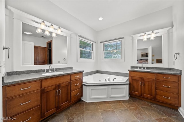 full bathroom featuring a garden tub, two vanities, and a sink