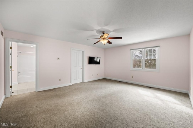 carpeted spare room featuring a ceiling fan, visible vents, and baseboards