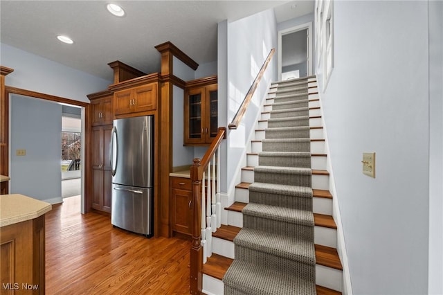 kitchen with light wood-style flooring, recessed lighting, light countertops, freestanding refrigerator, and brown cabinetry