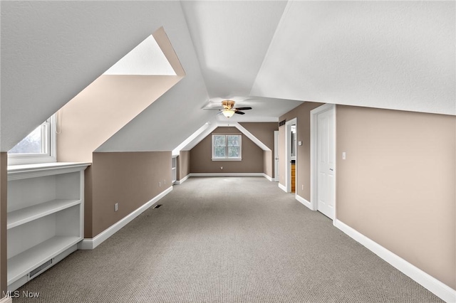 bonus room with lofted ceiling, carpet flooring, a ceiling fan, and baseboards