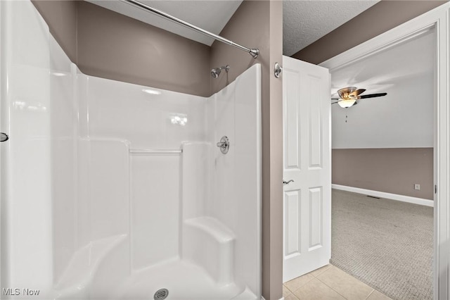 bathroom featuring a shower, tile patterned flooring, a textured ceiling, and baseboards