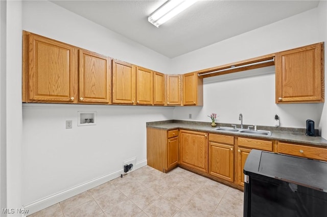 kitchen with brown cabinetry, dark countertops, a sink, and baseboards