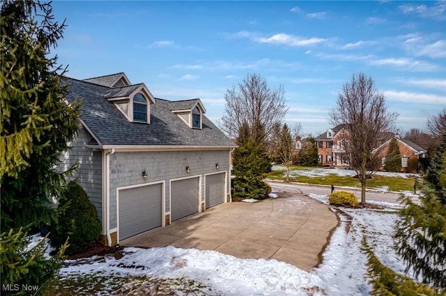 view of snowy exterior featuring a garage and a shingled roof