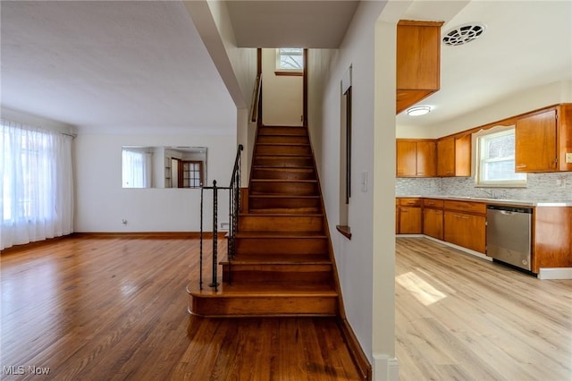 stairway with visible vents, baseboards, and wood finished floors