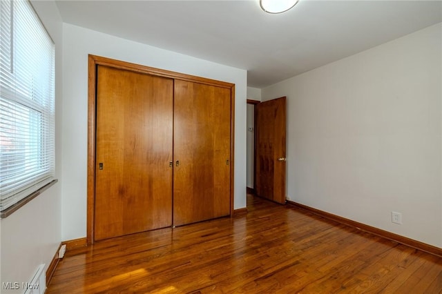 unfurnished bedroom featuring baseboards, a closet, and wood finished floors