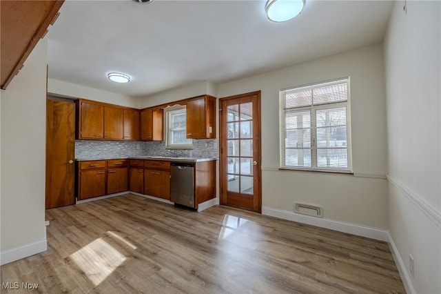 kitchen featuring light countertops, light wood-type flooring, backsplash, dishwasher, and brown cabinetry