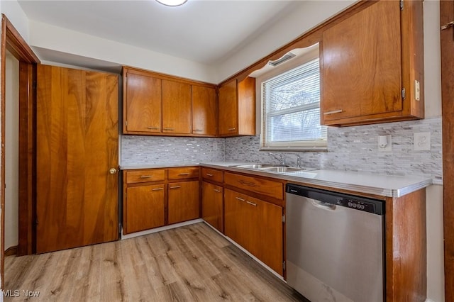 kitchen featuring a sink, brown cabinets, light countertops, and stainless steel dishwasher