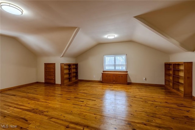 additional living space featuring lofted ceiling, hardwood / wood-style flooring, and baseboards