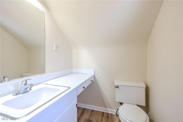 bathroom featuring toilet, baseboards, wood finished floors, and vanity