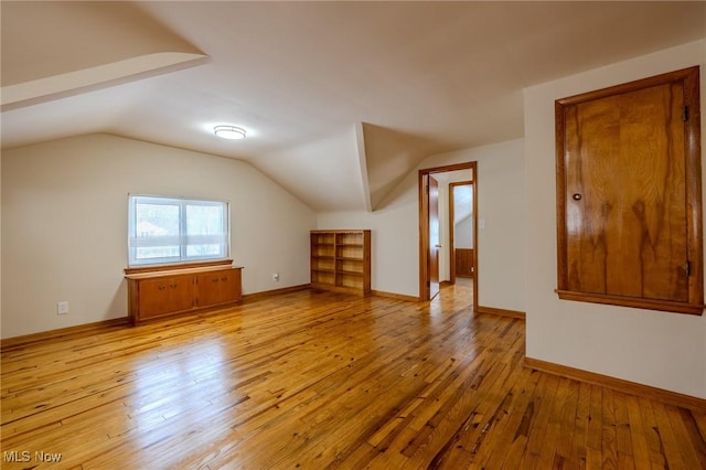 bonus room with lofted ceiling, baseboards, and light wood finished floors