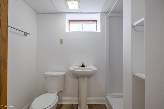 full bath featuring toilet, a sink, wood finished floors, baseboards, and walk in shower