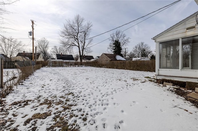 snowy yard featuring a sunroom and fence