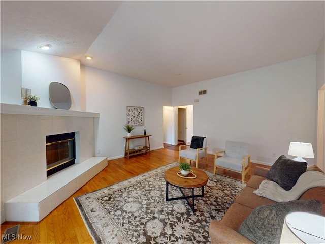 living area featuring visible vents, a fireplace, and wood finished floors