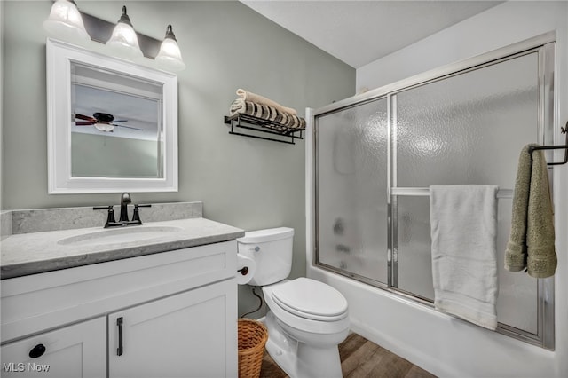 bathroom featuring ceiling fan, toilet, bath / shower combo with glass door, wood finished floors, and vanity