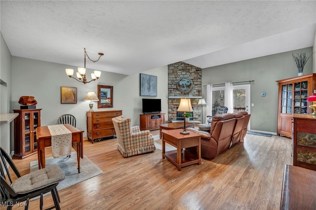 living room with light wood-type flooring, a chandelier, vaulted ceiling, and a textured ceiling