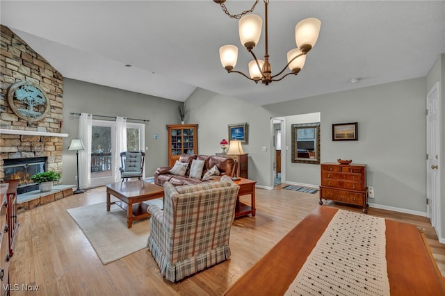 living room featuring a chandelier, a stone fireplace, light wood-style flooring, baseboards, and vaulted ceiling