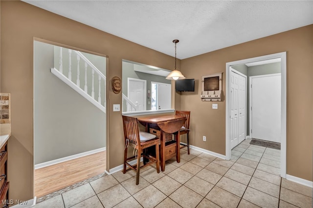 dining space with baseboards, stairway, a textured ceiling, and light tile patterned flooring