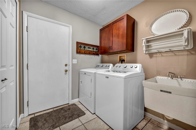 laundry room featuring light tile patterned floors, cabinet space, washing machine and dryer, a sink, and a textured ceiling