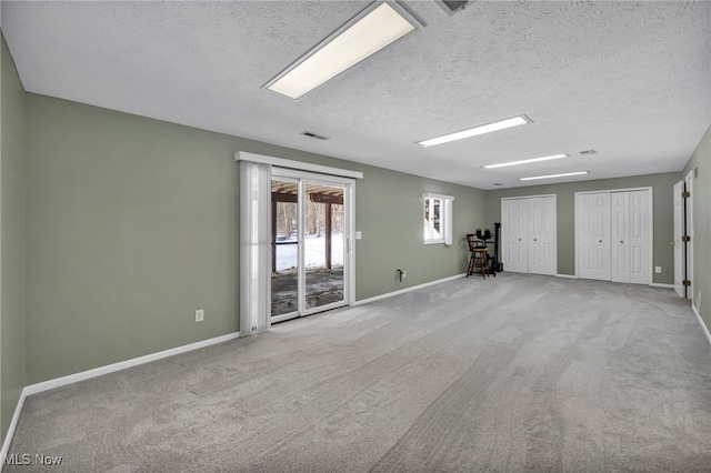 empty room featuring carpet flooring, a textured ceiling, and baseboards