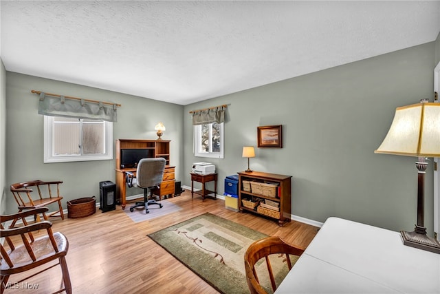 home office featuring a textured ceiling, baseboards, and wood finished floors