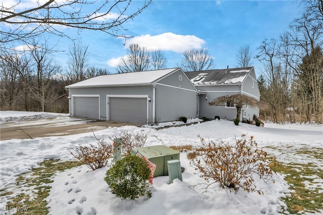 snow covered property featuring an attached garage