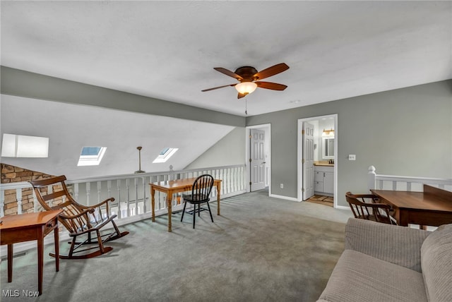 interior space with baseboards, visible vents, a ceiling fan, lofted ceiling with skylight, and carpet floors