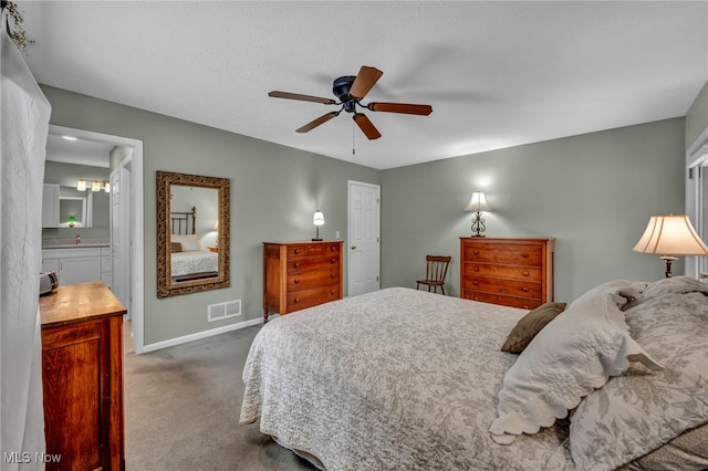 bedroom featuring ceiling fan, ensuite bathroom, visible vents, baseboards, and carpet