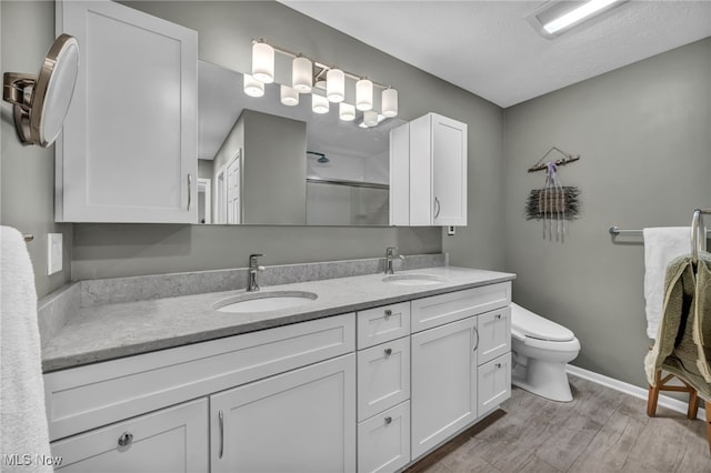 full bath featuring a stall shower, wood finished floors, a sink, and double vanity