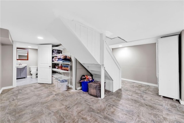 finished below grade area with baseboards, a sink, and recessed lighting