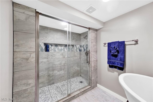 full bathroom with a soaking tub, a shower stall, visible vents, and baseboards