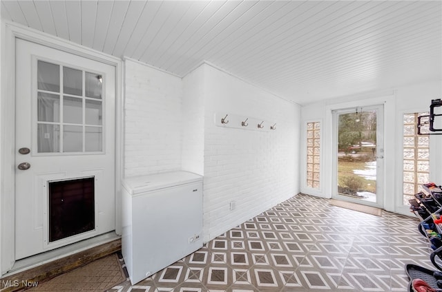 mudroom with wood ceiling, brick wall, and tile patterned floors