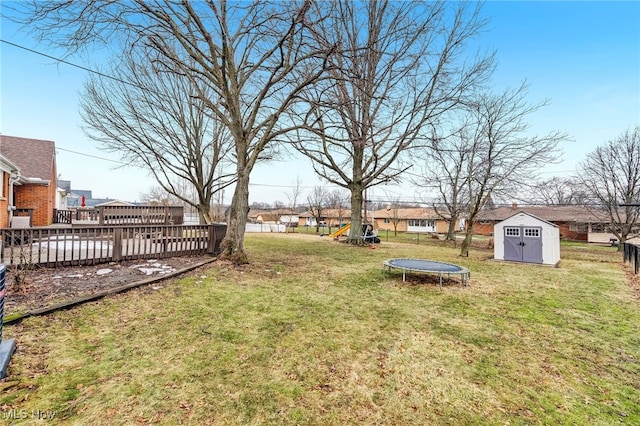 view of yard with a trampoline, an outdoor structure, and a storage unit