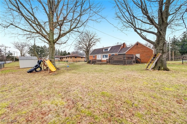 view of yard featuring a playground, a wooden deck, and fence