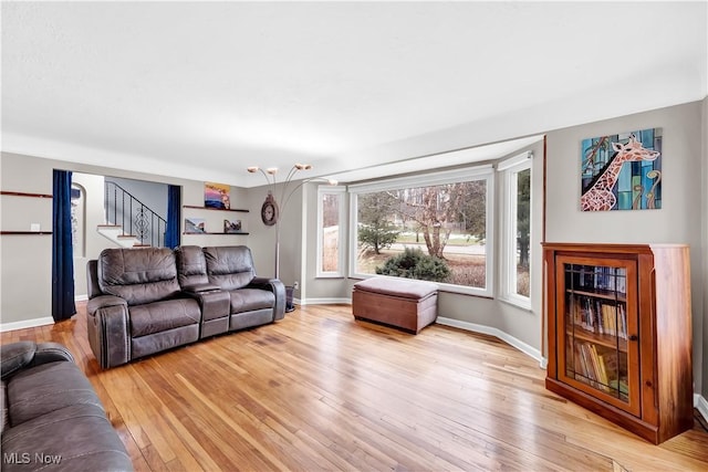 living room featuring stairs, baseboards, and light wood-style floors